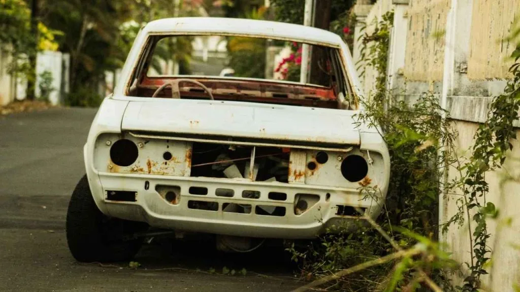 a white junk car parked on the roadside